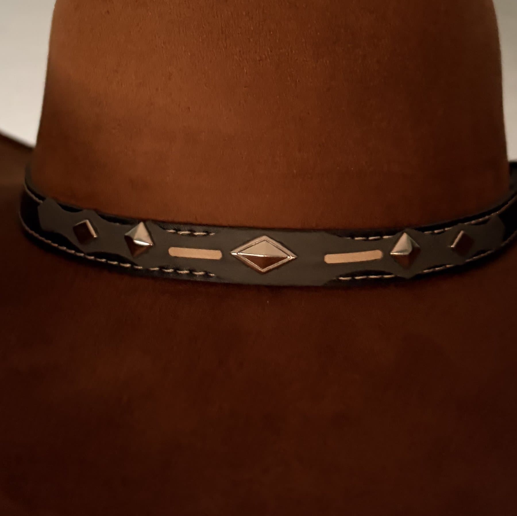 Rust felt hat, close on the leather band: nickel pyramid studs and a diamond concho.