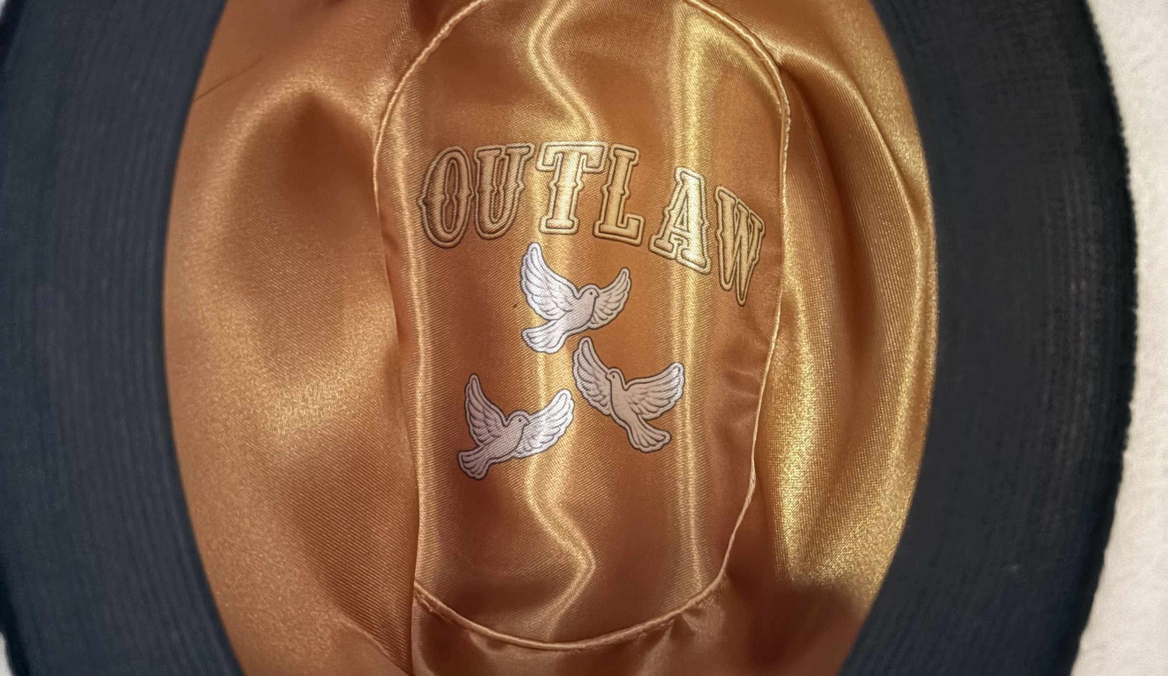 Black felt hat turned over: copper satin lining with OUTLAW and three doves.